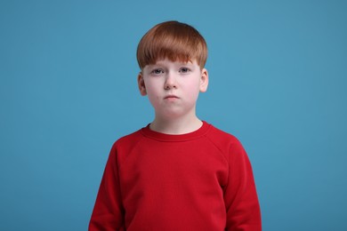 Photo of Portrait of sad little boy on light blue background