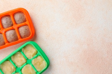 Photo of Apple and banana puree in ice cube trays on beige table, flat lay. Space for text