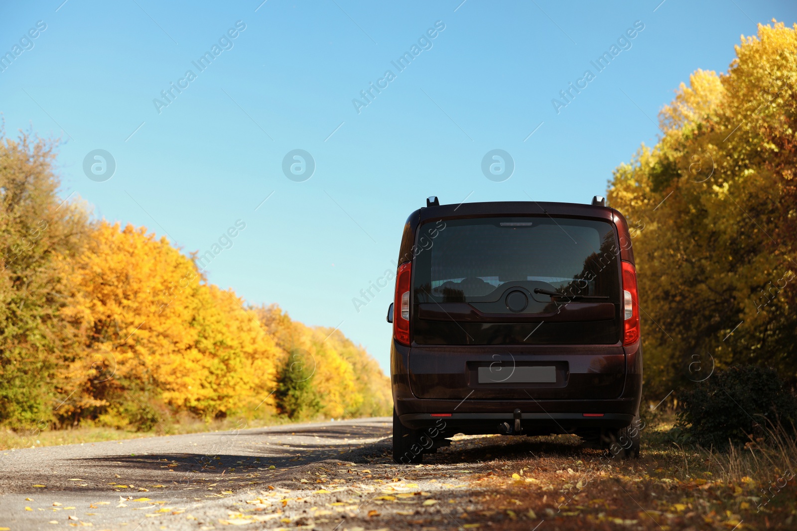 Photo of Car parked on country road near autumn forest. Space for text