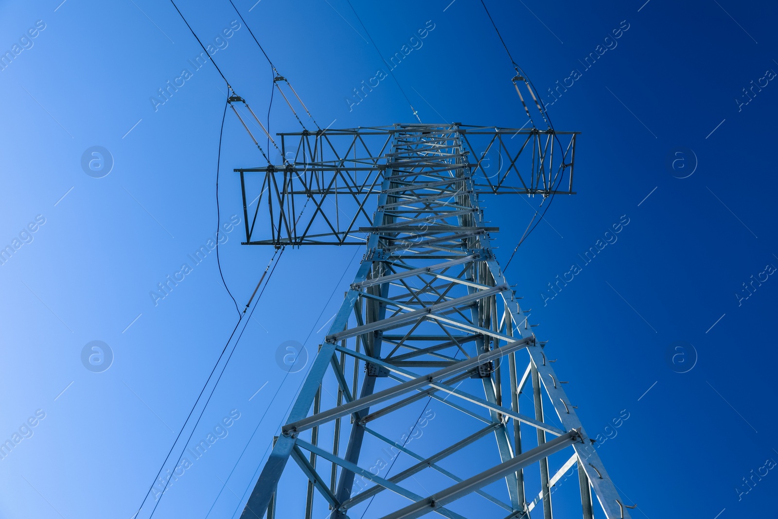 Photo of Modern high voltage tower against blue sky, low angle view