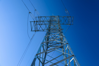 Photo of Modern high voltage tower against blue sky, low angle view