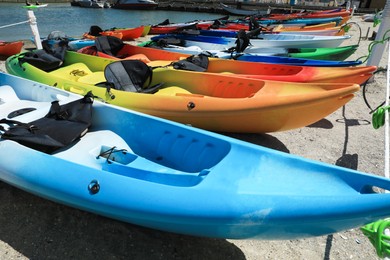 Many colorful kayaks on sand near sea