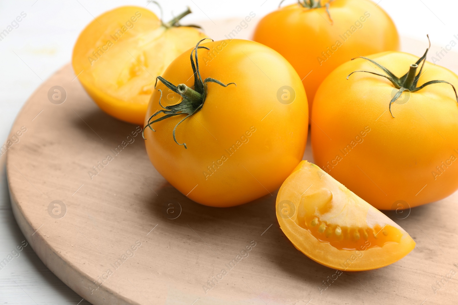 Photo of Ripe yellow tomatoes on wooden board, closeup