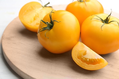 Photo of Ripe yellow tomatoes on wooden board, closeup