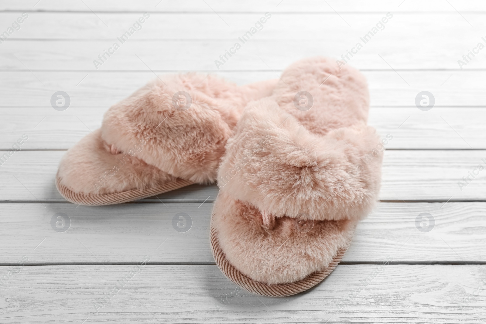 Photo of Pair of stylish soft slippers on white wooden background