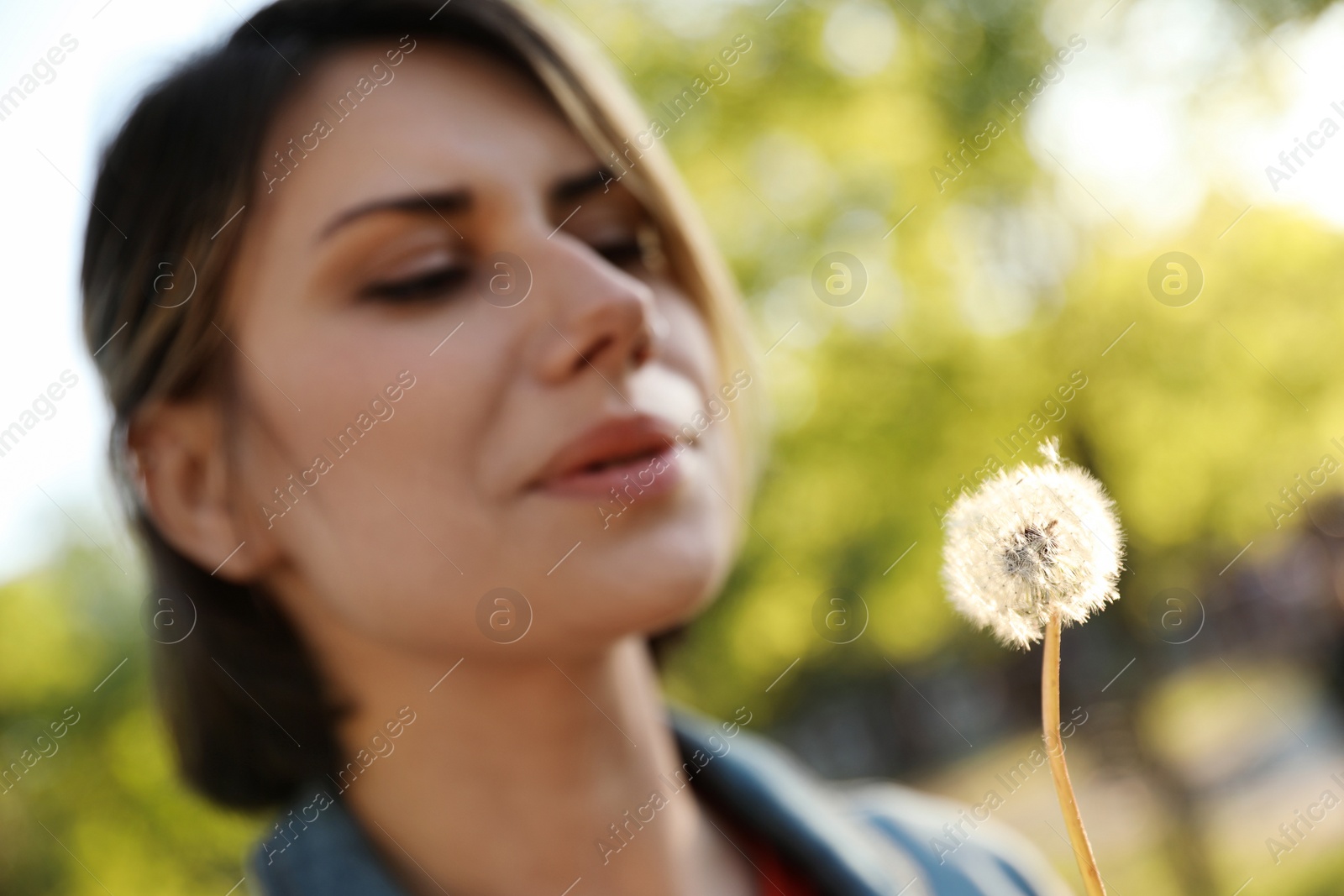 Photo of Young woman with dandelion in park on sunny day, closeup. Allergy free concept