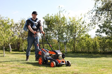 Man cutting green grass with lawn mower in garden