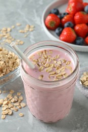 Photo of Jar of tasty berry oatmeal smoothie on grey table