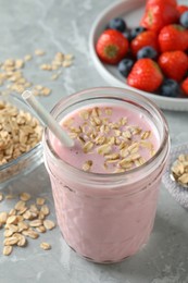 Jar of tasty berry oatmeal smoothie on grey table