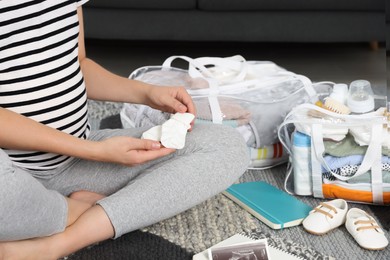 Photo of Pregnant woman packing bag for maternity hospital at home, closeup