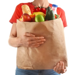 Woman holding paper bag with different groceries on white background, closeup view