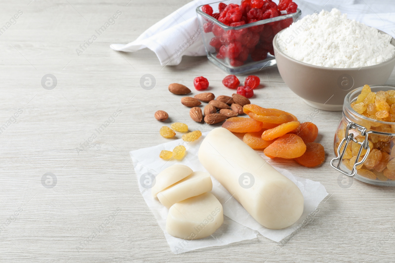 Photo of Marzipan and other ingredients for homemade Stollen on white wooden table. Baking traditional German Christmas bread