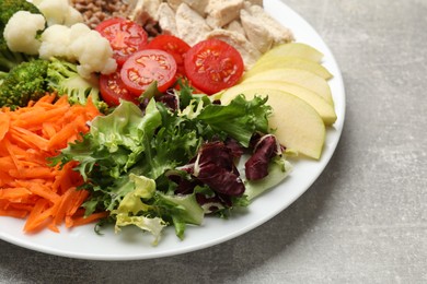 Photo of Balanced diet and healthy foods. Plate with different delicious products on grey table, closeup