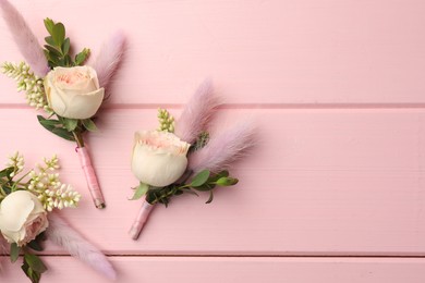 Many small stylish boutonnieres on pink wooden table, flat lay. Space for text