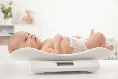 Cute little baby lying on scales in light room