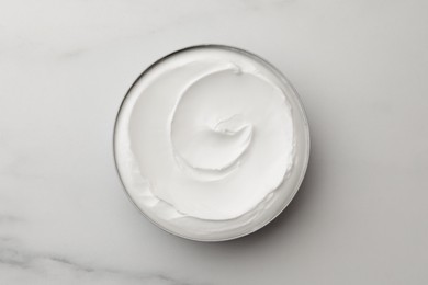 Photo of Jar of face cream on white marble table, top view