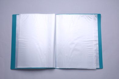 Photo of File folder with punched pockets and paper sheets on light grey background, top view