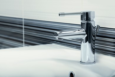 Clean white sink with shiny water tap in bathroom