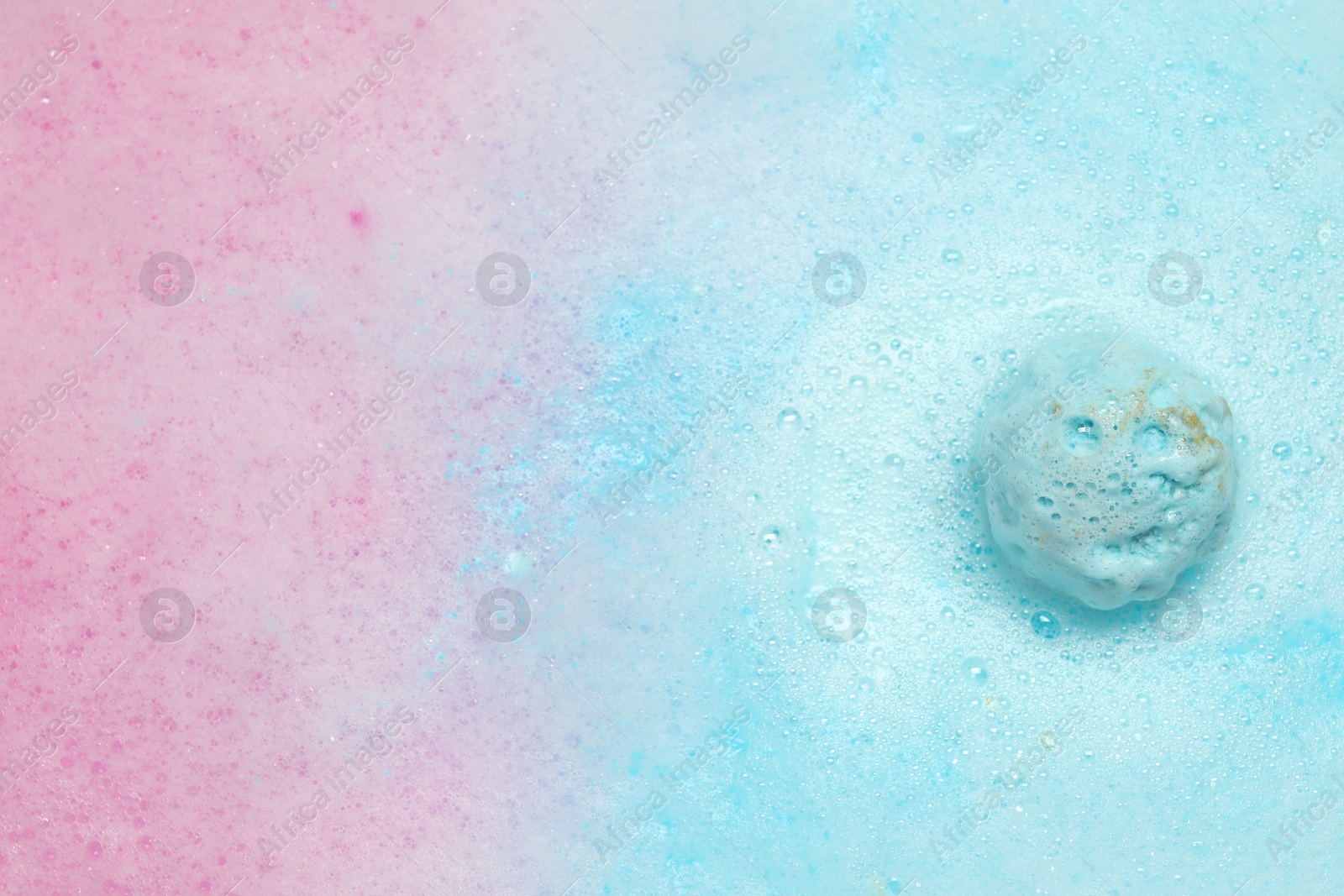 Photo of Light blue bath bomb dissolving in water. Space for text