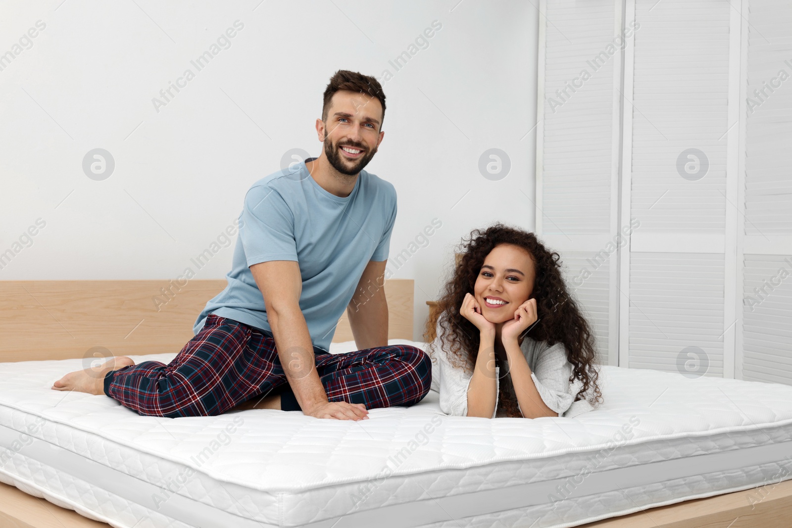 Photo of Happy couple on bed with comfortable mattress at home