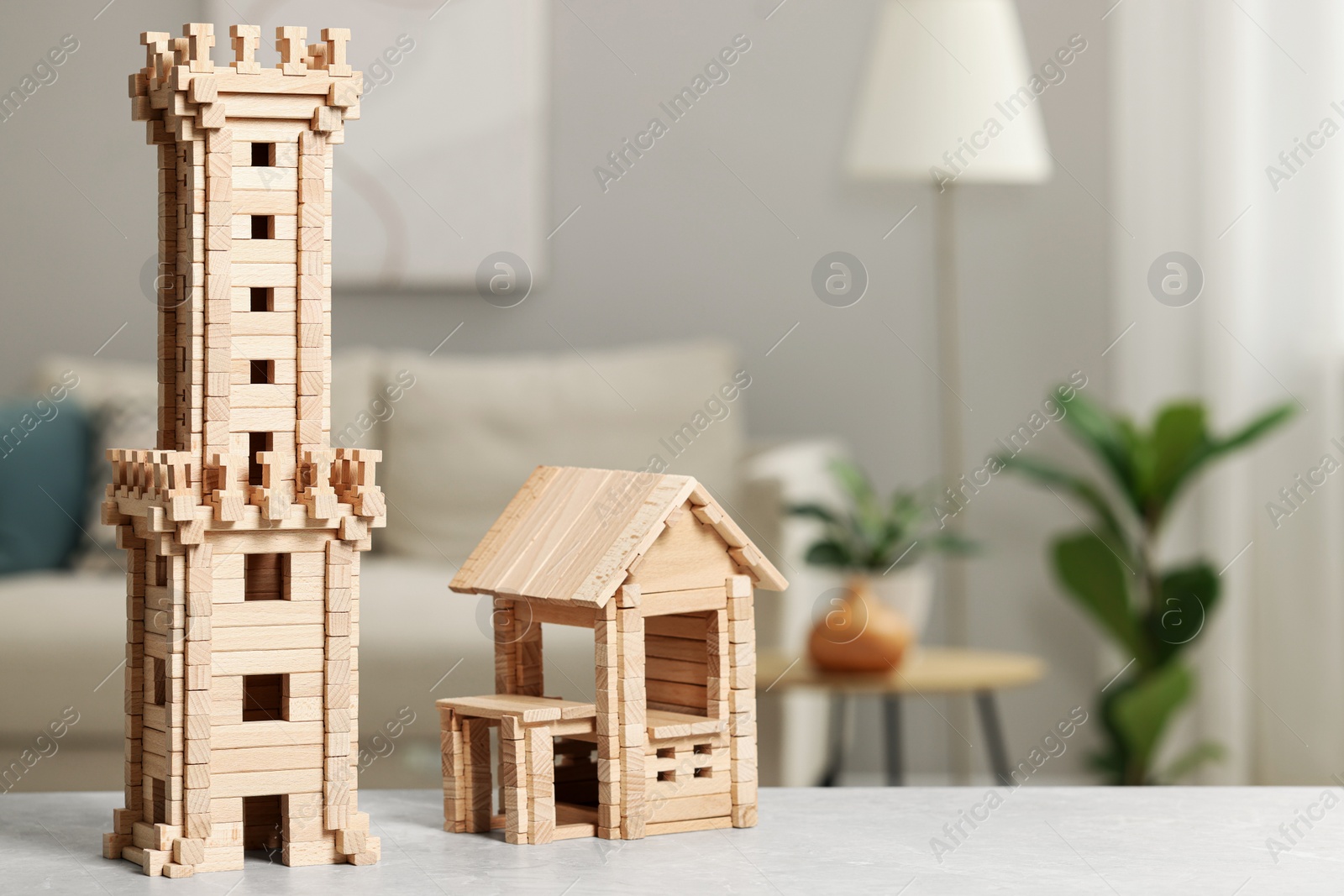 Photo of Wooden tower and house on light grey table indoors, space for text. Children's development
