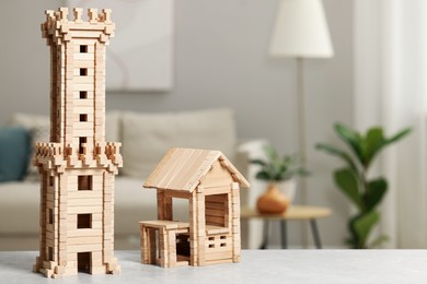 Wooden tower and house on light grey table indoors, space for text. Children's development