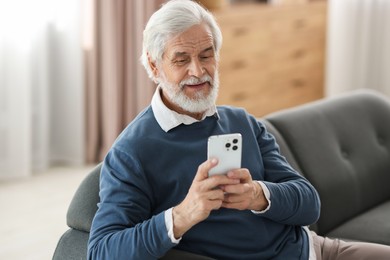 Photo of Portrait of happy grandpa using smartphone indoors