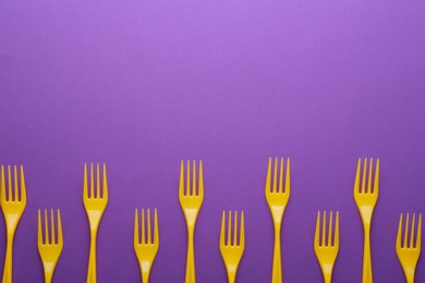 Photo of Plastic forks on color background, top view with space for text. Picnic table setting