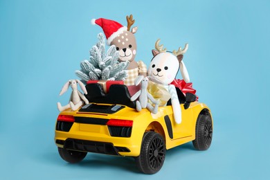 Photo of Child's electric car with toys, gift boxes and Christmas decor on light blue background