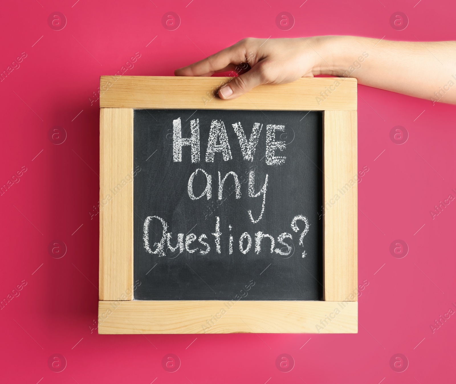 Photo of Woman holding blackboard with phrase HAVE ANY QUESTIONS on pink background, closeup