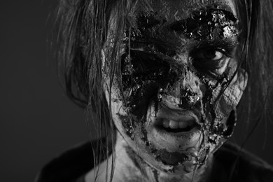 Scary zombie on dark background, black and white effect. Halloween monster