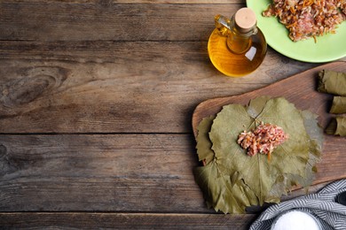 Ingredients for preparing stuffed grape leaves on wooden table, flat lay. Space for text