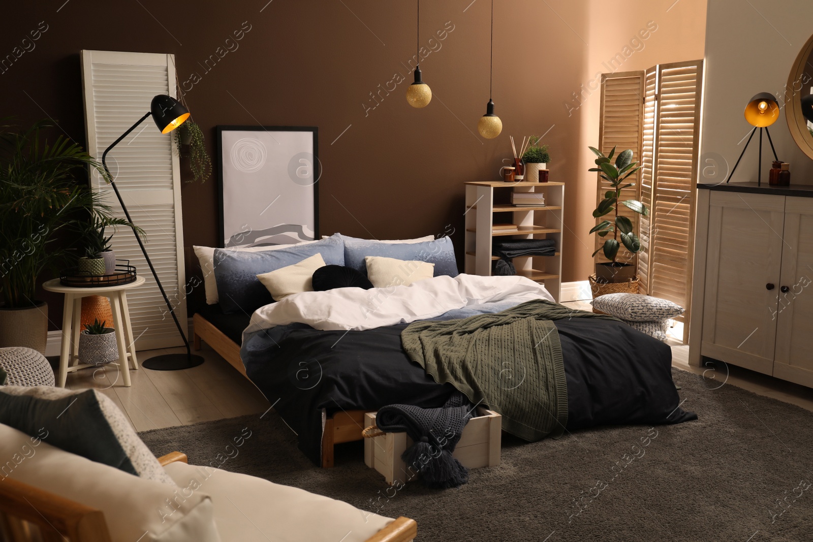 Photo of Stylish room interior with large bed near brown wall