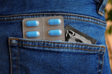 Jeans with pills and condom in pocket, closeup. Potency problem
