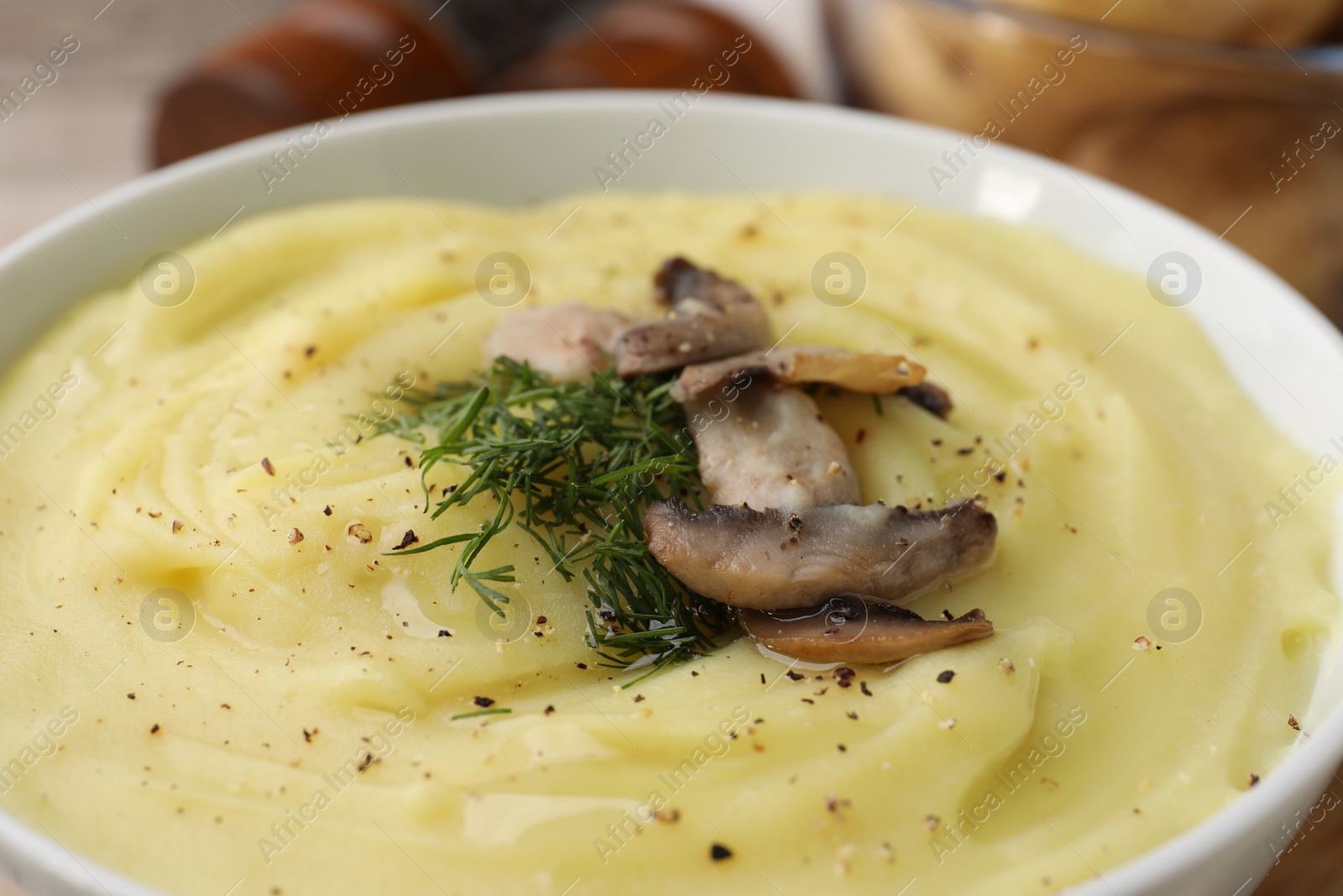 Photo of Bowl of tasty cream soup with mushrooms and dill on table, closeup