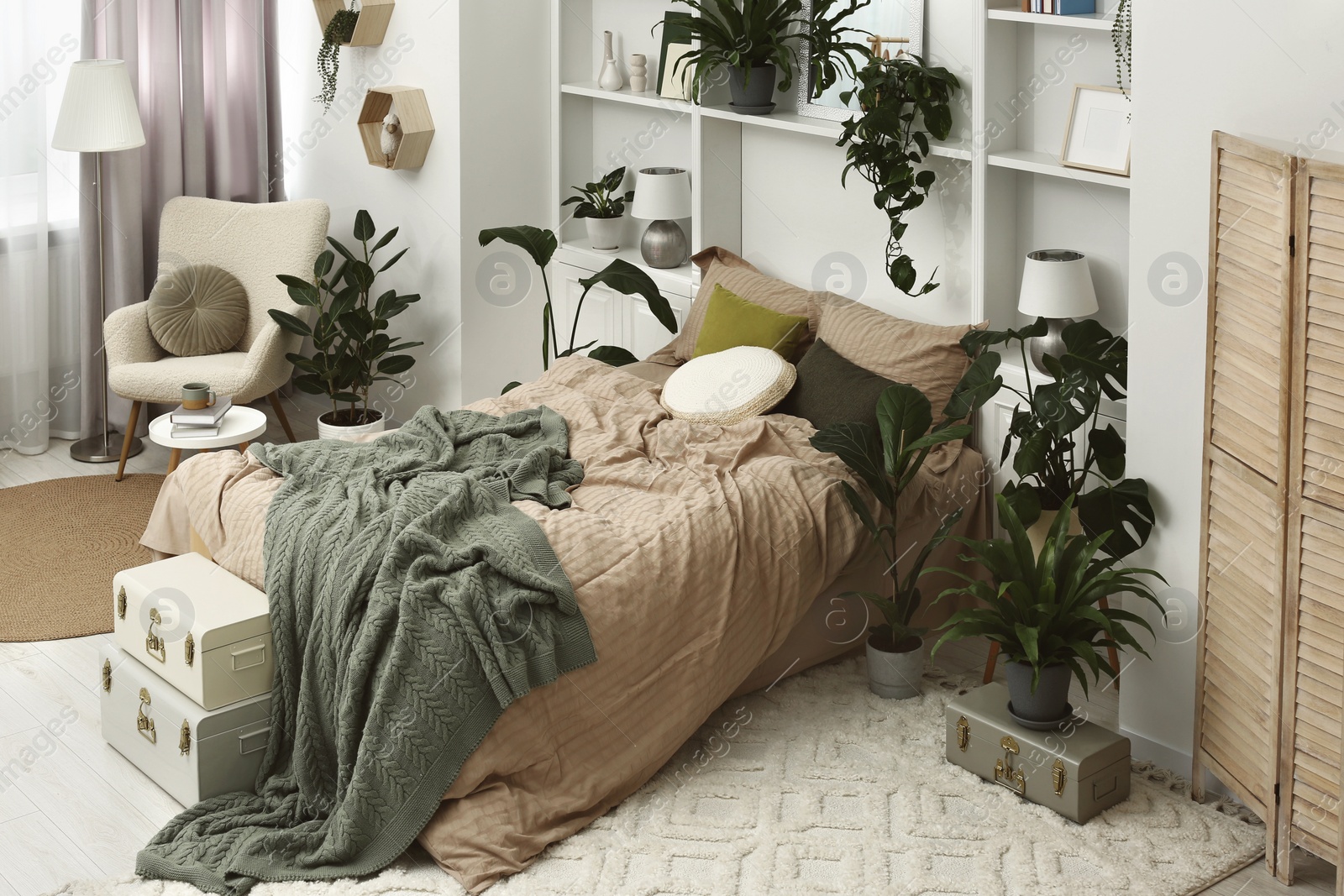 Photo of Stylish bedroom with comfortable bed and different houseplants. Interior design