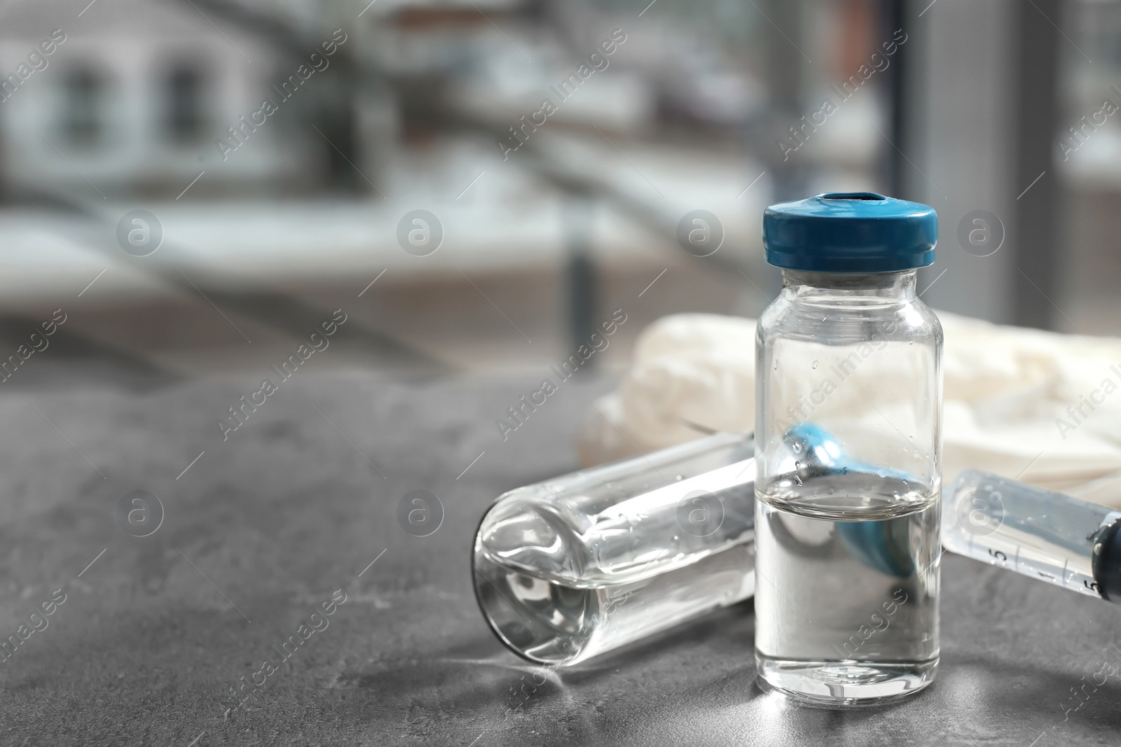 Photo of Vials and syringe with medicine on blurred background. Vaccination concept