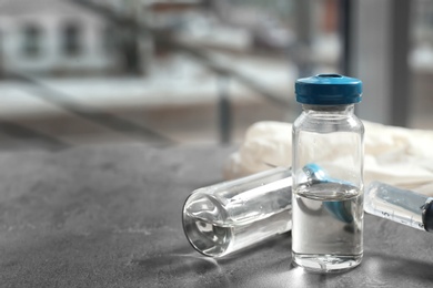 Vials and syringe with medicine on blurred background. Vaccination concept