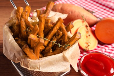 Photo of Sweet potato fries and ketchup on wooden table, closeup