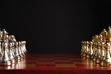 Photo of Many chess pieces on wooden checkerboard against black background, closeup. Space for text