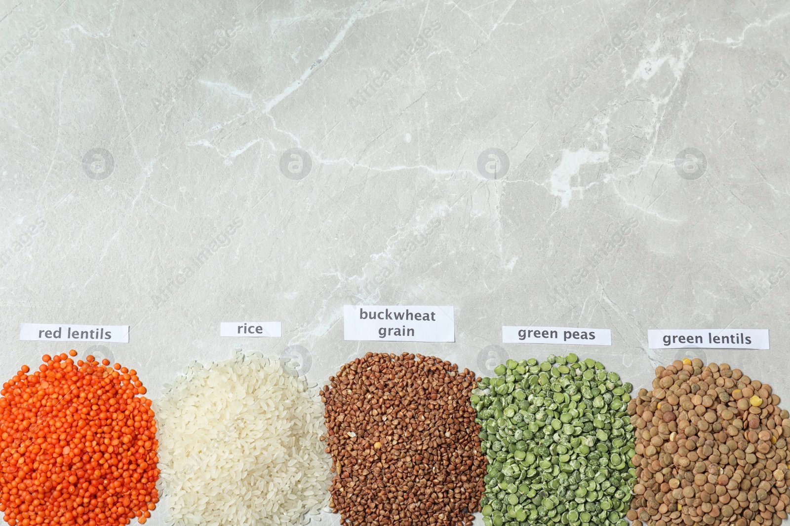 Photo of Flat lay composition with different types of legumes and cereals on grey marble table, space for text. Organic grains