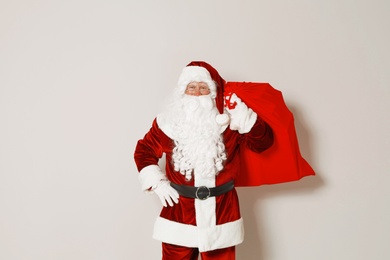 Authentic Santa Claus with bag full of gifts on grey background