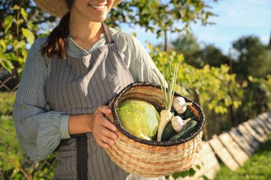 Photo of Woman with basket of different fresh ripe vegetables on farm, closeup