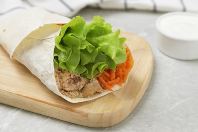 Photo of Delicious tortilla wrap with tuna on grey table, closeup