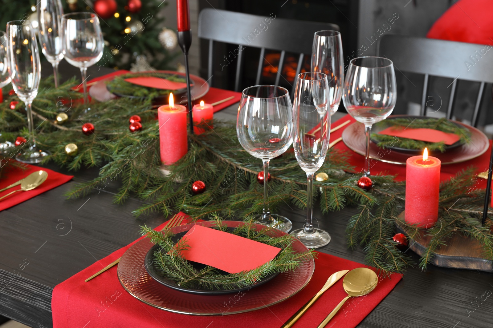 Photo of Elegant Christmas table setting with dishware and burning candles in festively decorated room