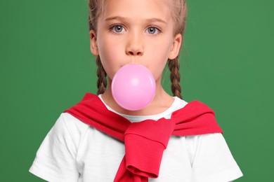 Photo of Girl blowing bubble gum on green background