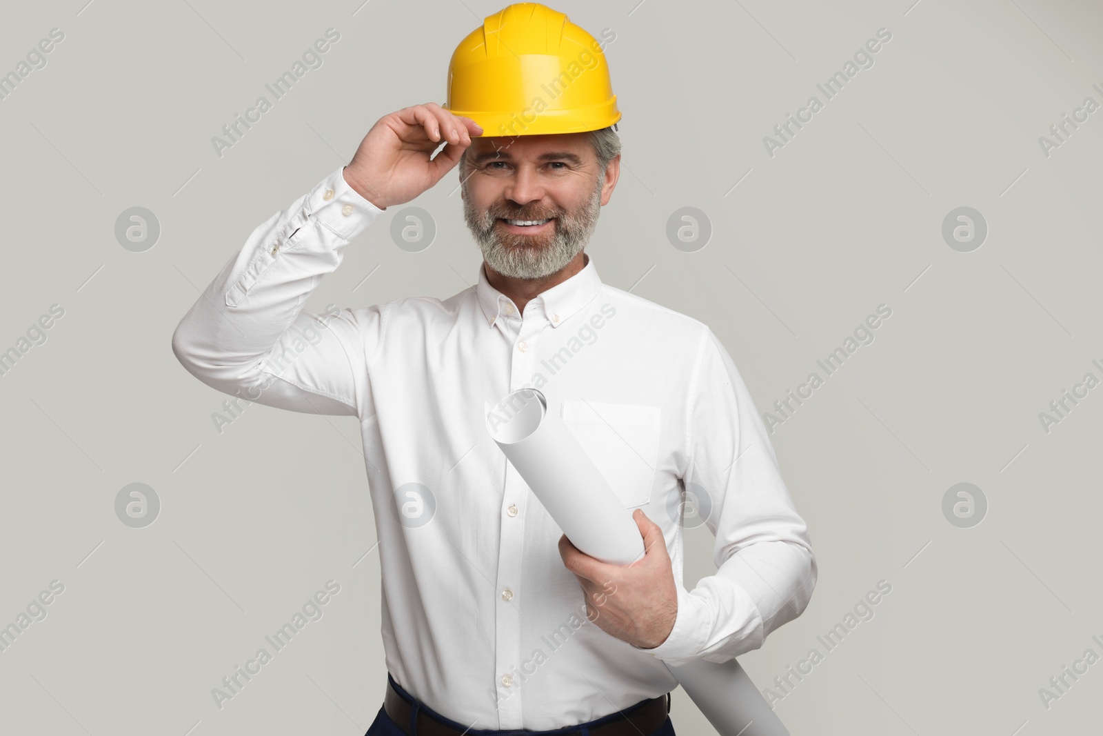 Photo of Architect in hard hat holding draft on grey background