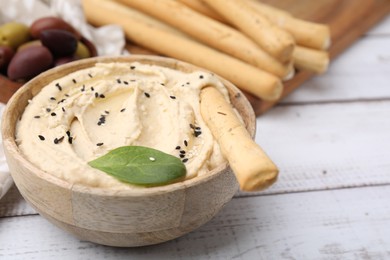 Photo of Delicious hummus with grissini stick on white wooden table, closeup