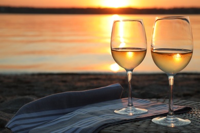 Glasses of delicious wine on riverside at sunset