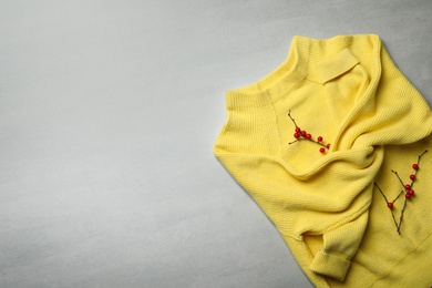 Yellow warm sweater on light grey table, top view. Space for text